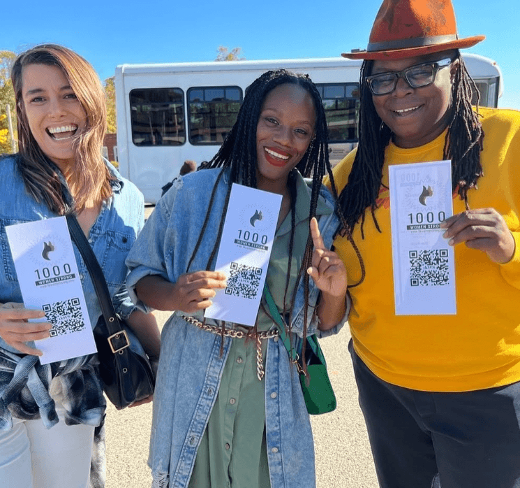 Organizers from 1000 Women Strong smiling and holding campaign literature.