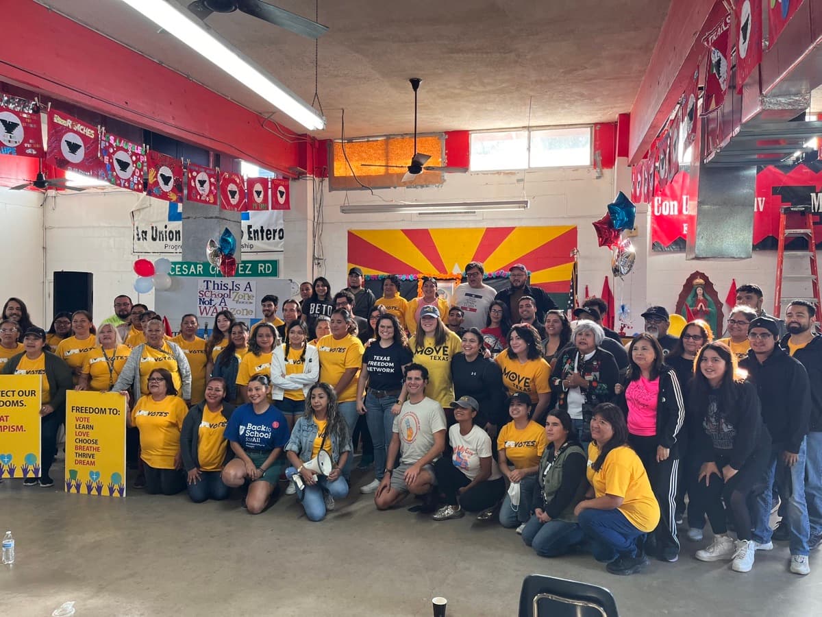 About 40 LUPE Votes members in yellow shirts pose together in a meeting hall.