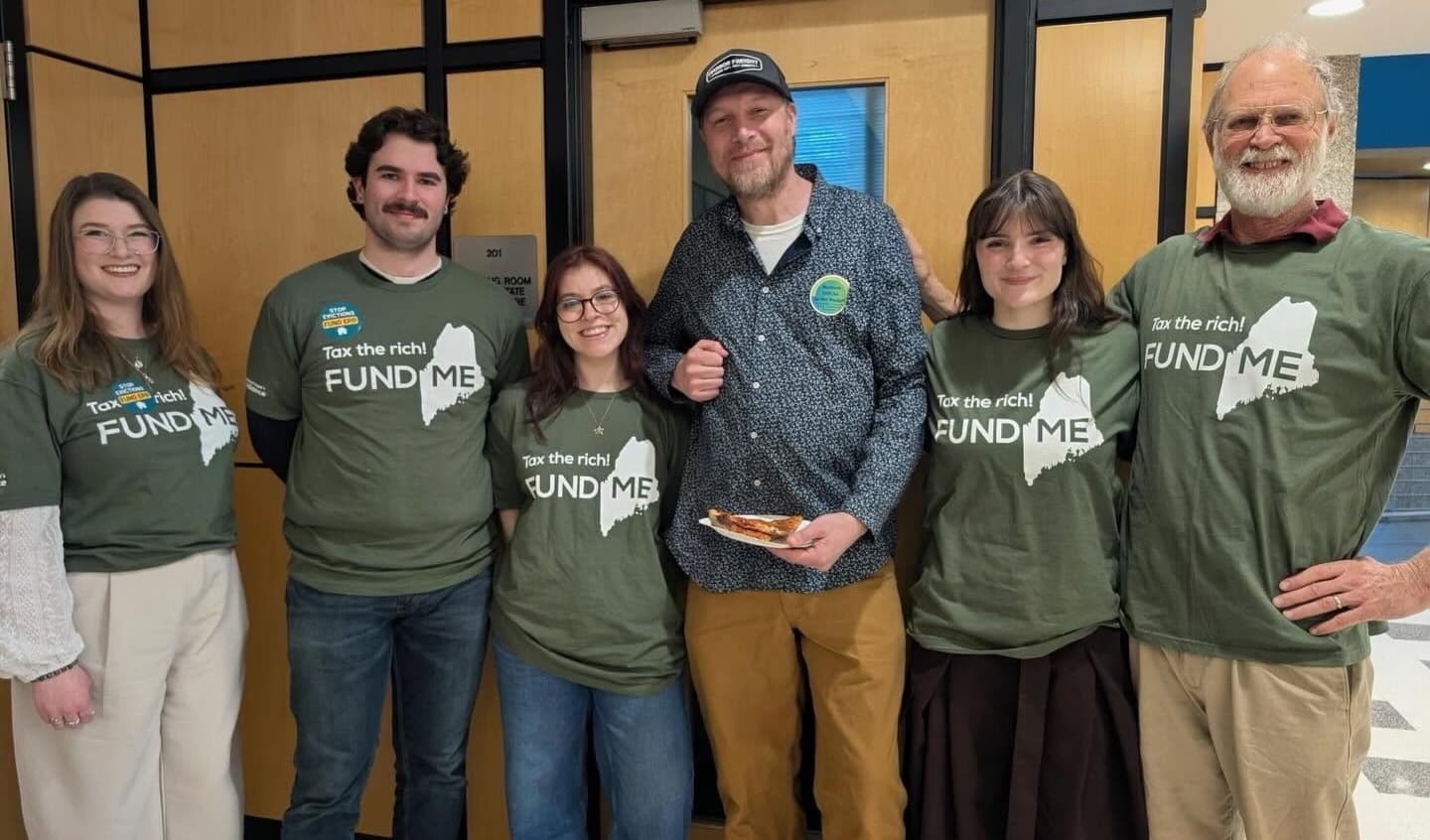 Maine People’s Alliance organizers in “Tax the rich, Fund ME” shirts pose together.