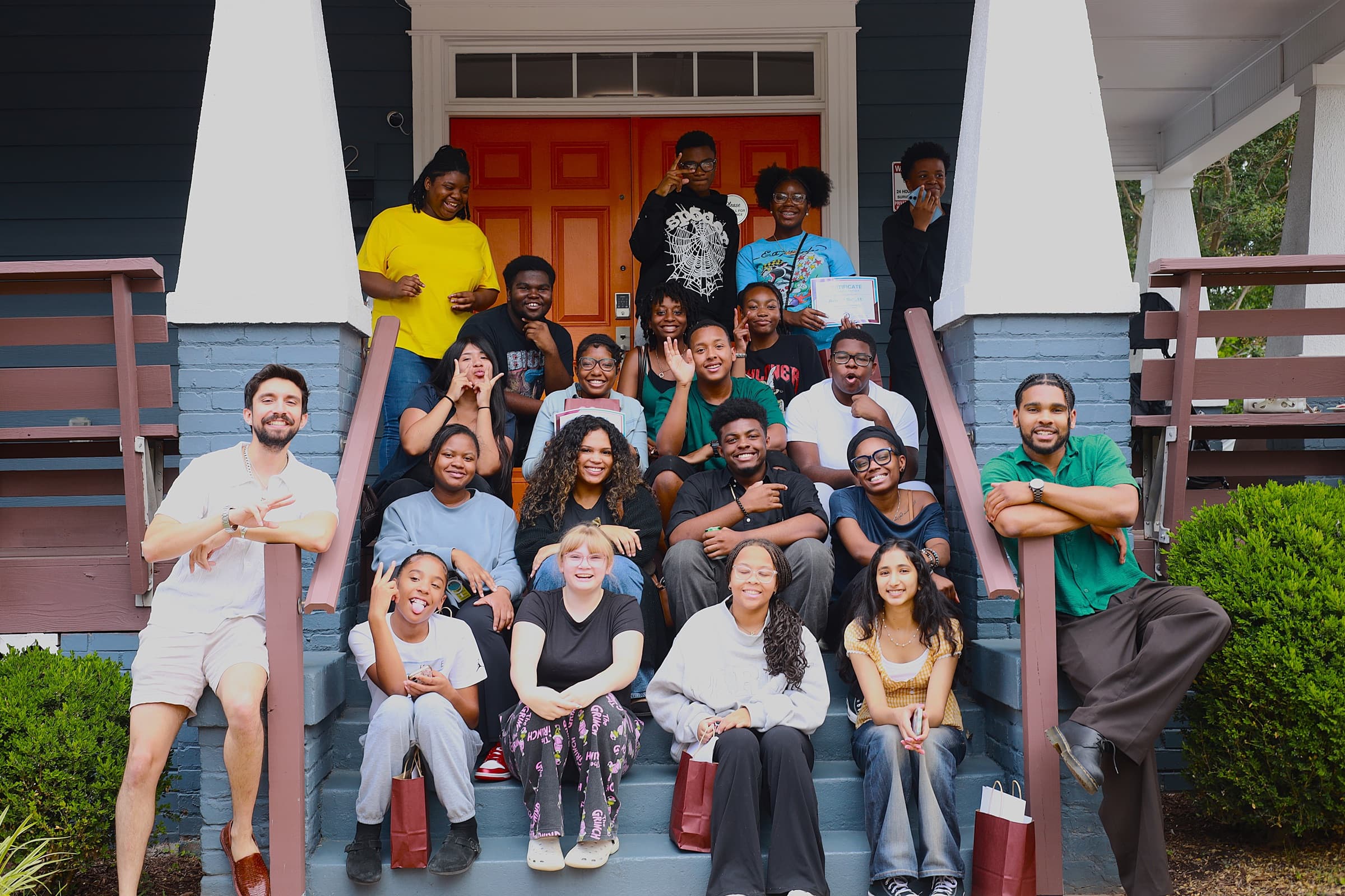 About two dozen young people and organizers with Education Justice Alliance smile together on the front steps and porch of a house in North Carolina