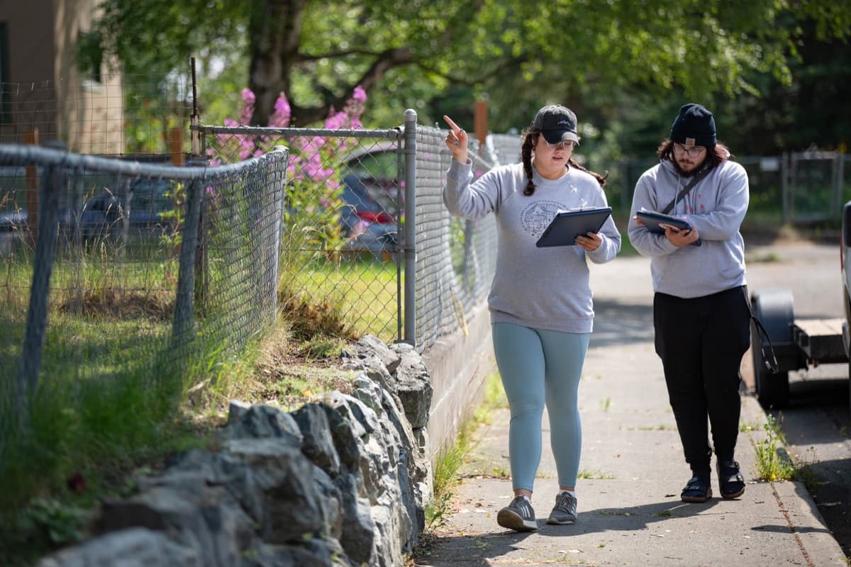 Two canvassers with tablets walk a residential street in Alaska.