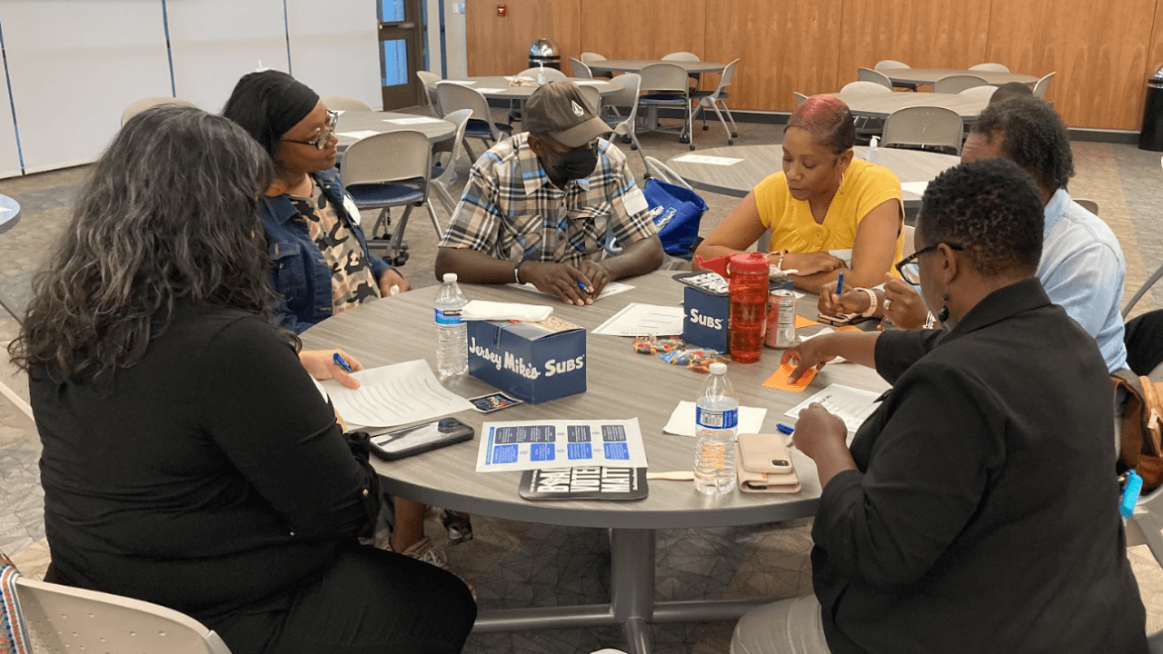 Members of the Black Leadership Action Coalition of Kentucky work through handouts around a table at a community meeting