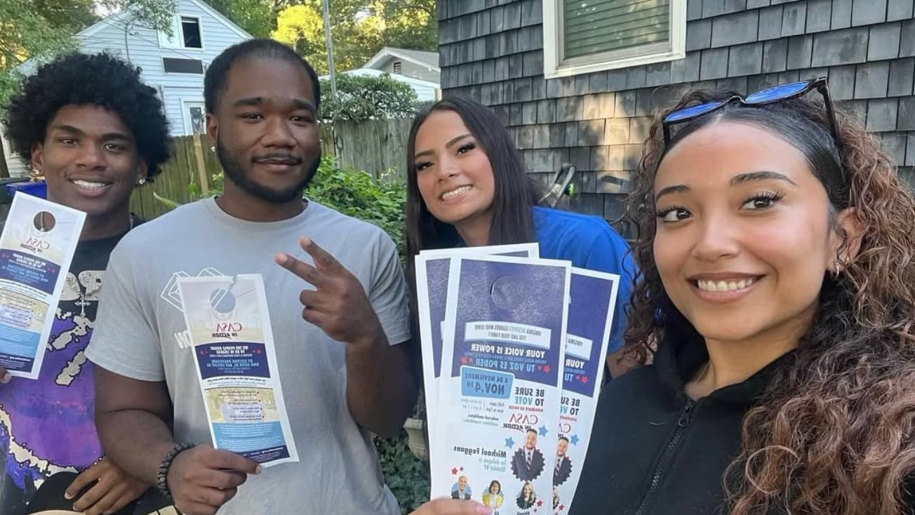 Four CASA in Action Virginia canvassers hold voter guides and smile.