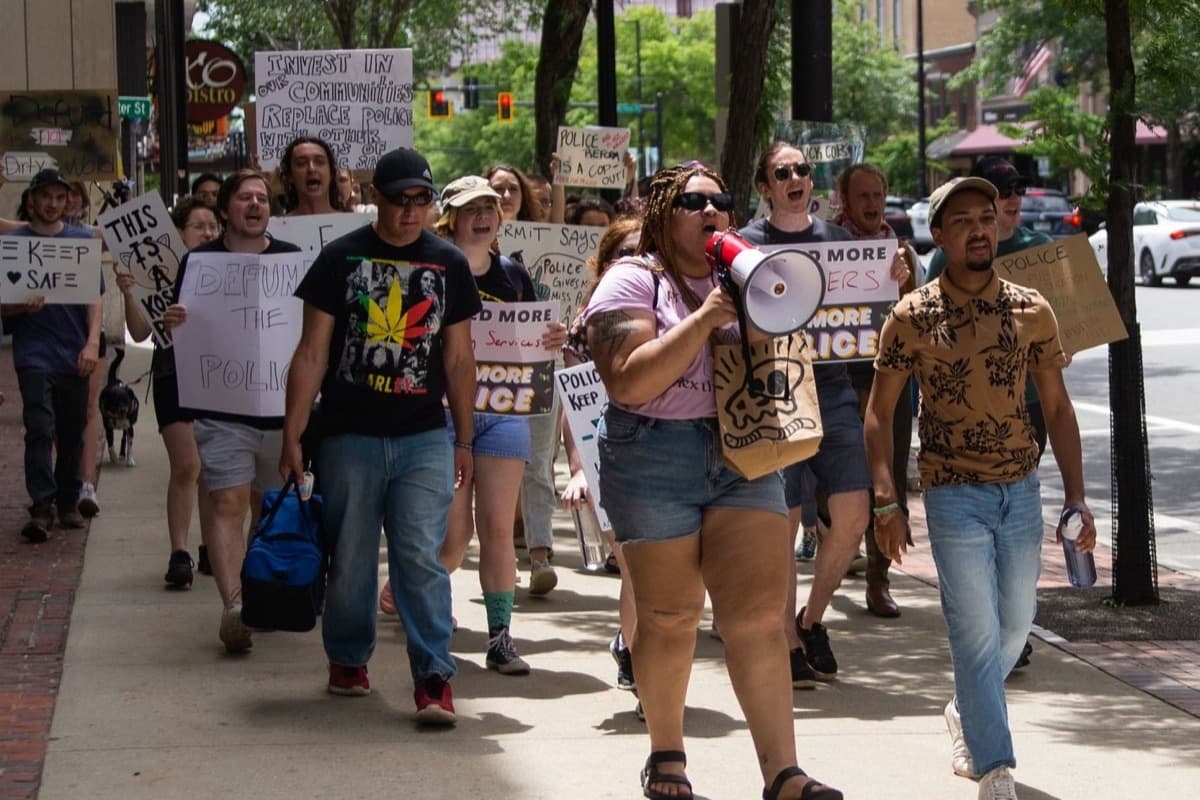 New Hampshire Youth Movement members march down a street with signs and a megaphone.
