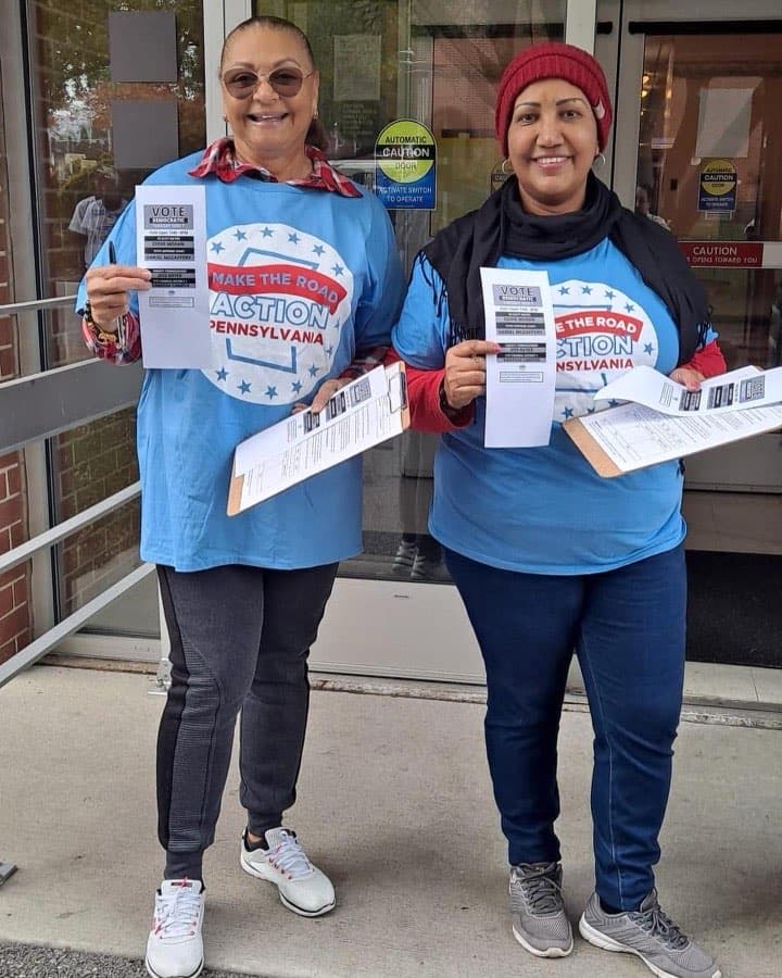 Two Make the Road Action Pennsylvania volunteers hold voter flyers outside a polling place.