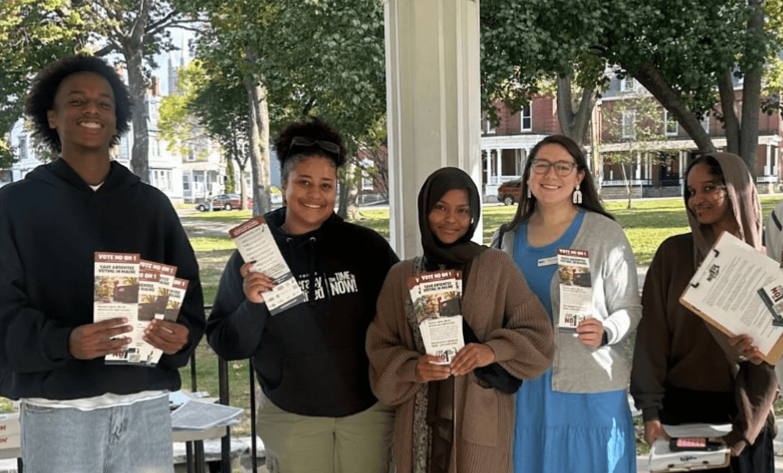 Four young Community Action Alliance volunteers hold voter flyers while getting out the vote in Maine.