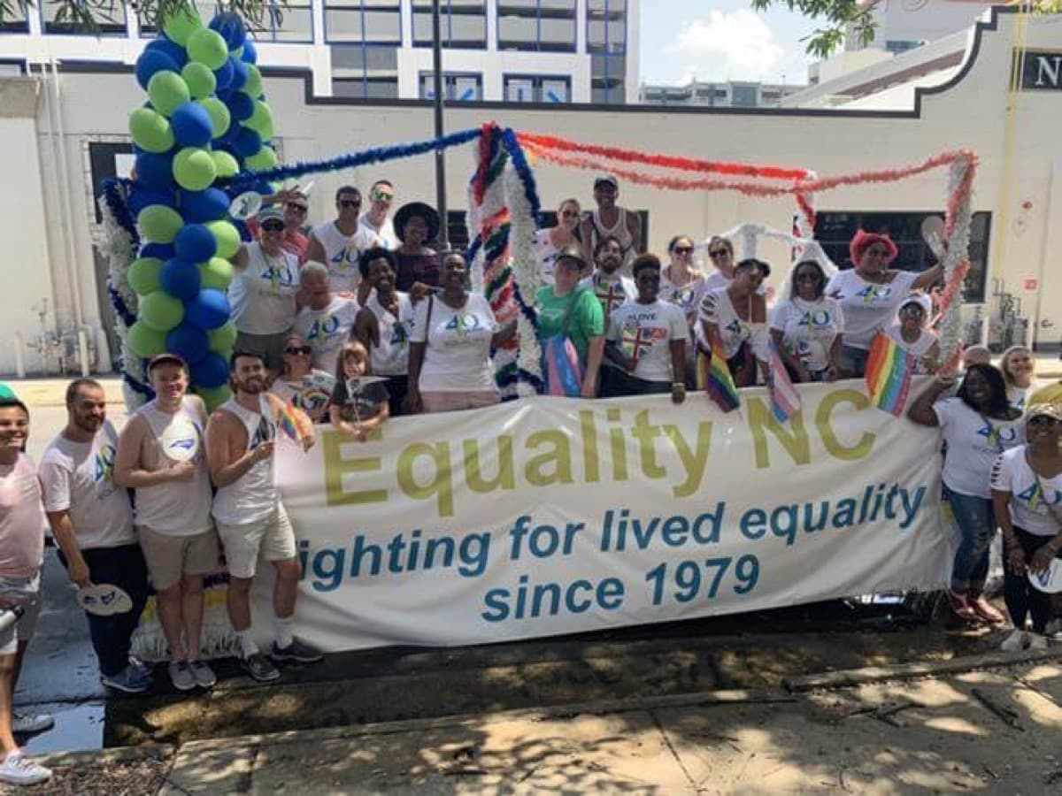 A large group marches behind an Equality NC banner reading “fighting for lived equality since 1979.”