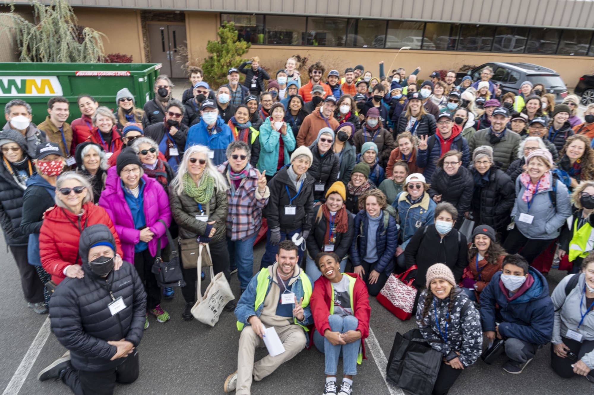 A large group of Seed the Vote volunteers, many wearing name tags, gather in a parking lot before a canvass in Reno.