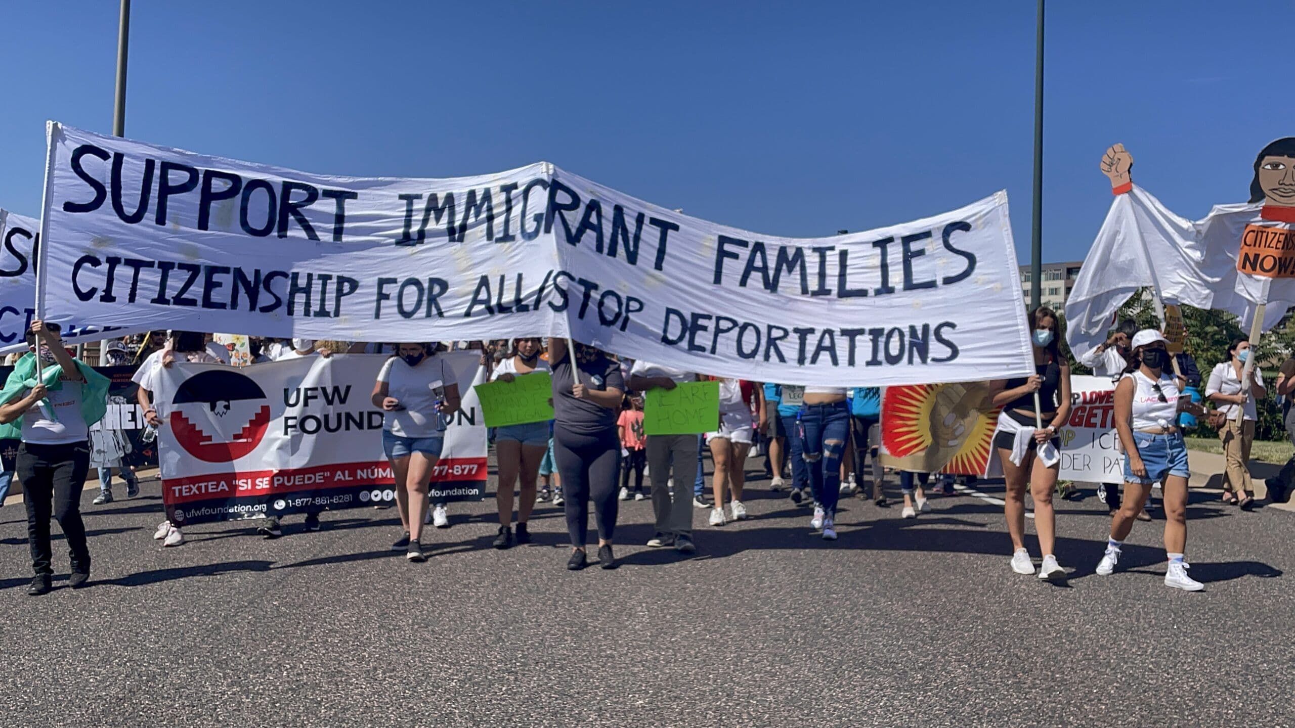 Marchers carry a banner reading “Support immigrant families” at a Colorado immigrant rights march.