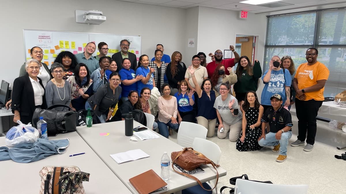 About 35 FLIC Votes members cheer together in a training room.