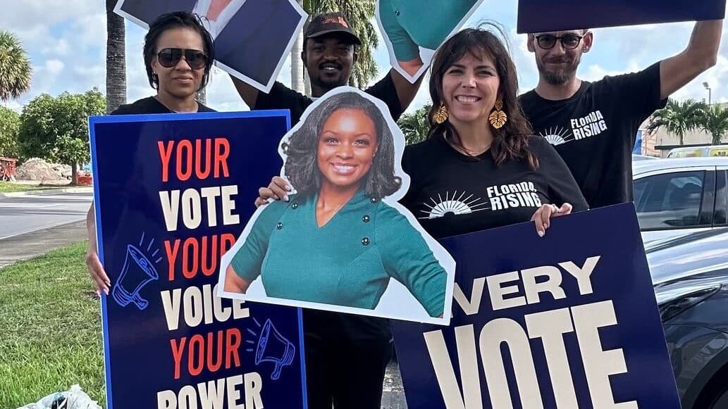 Florida Rising members hold “Your vote, your voice, your power” and “Every vote” signs outdoors.