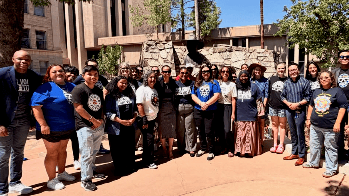 About 30 Activate 48 coalition members in Our Voice Our Vote, LUCHA and Chispa shirts pose together in the Arizona State Capitol plaza after the 2026 primary
