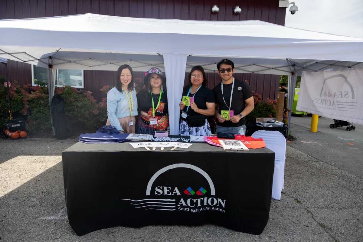 Four SEA Action organizers stand behind their table at an outdoor event in Green Bay.