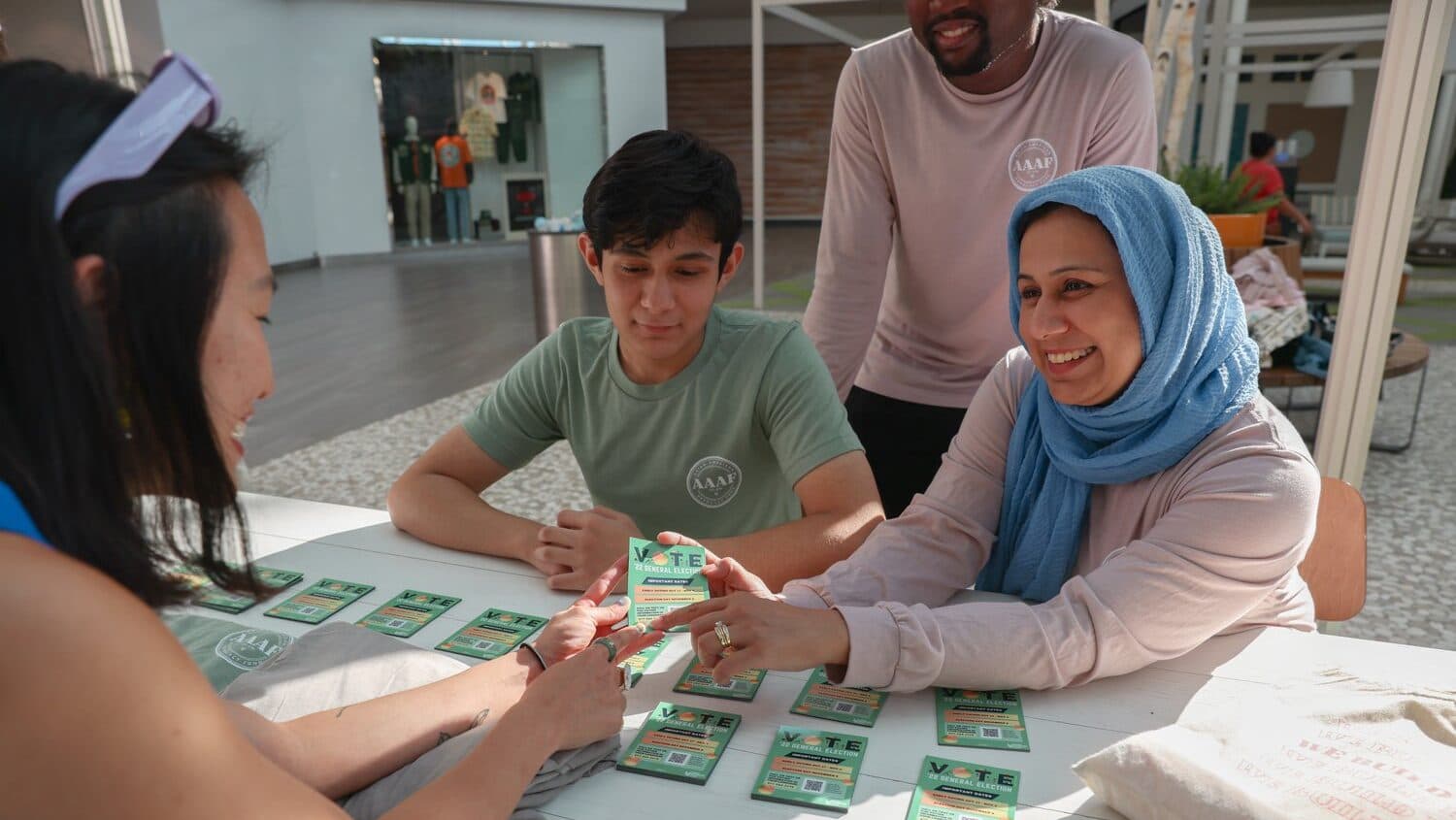 Volunteers at an Asian American Advocacy Fund table hand out voter information to a young voter.