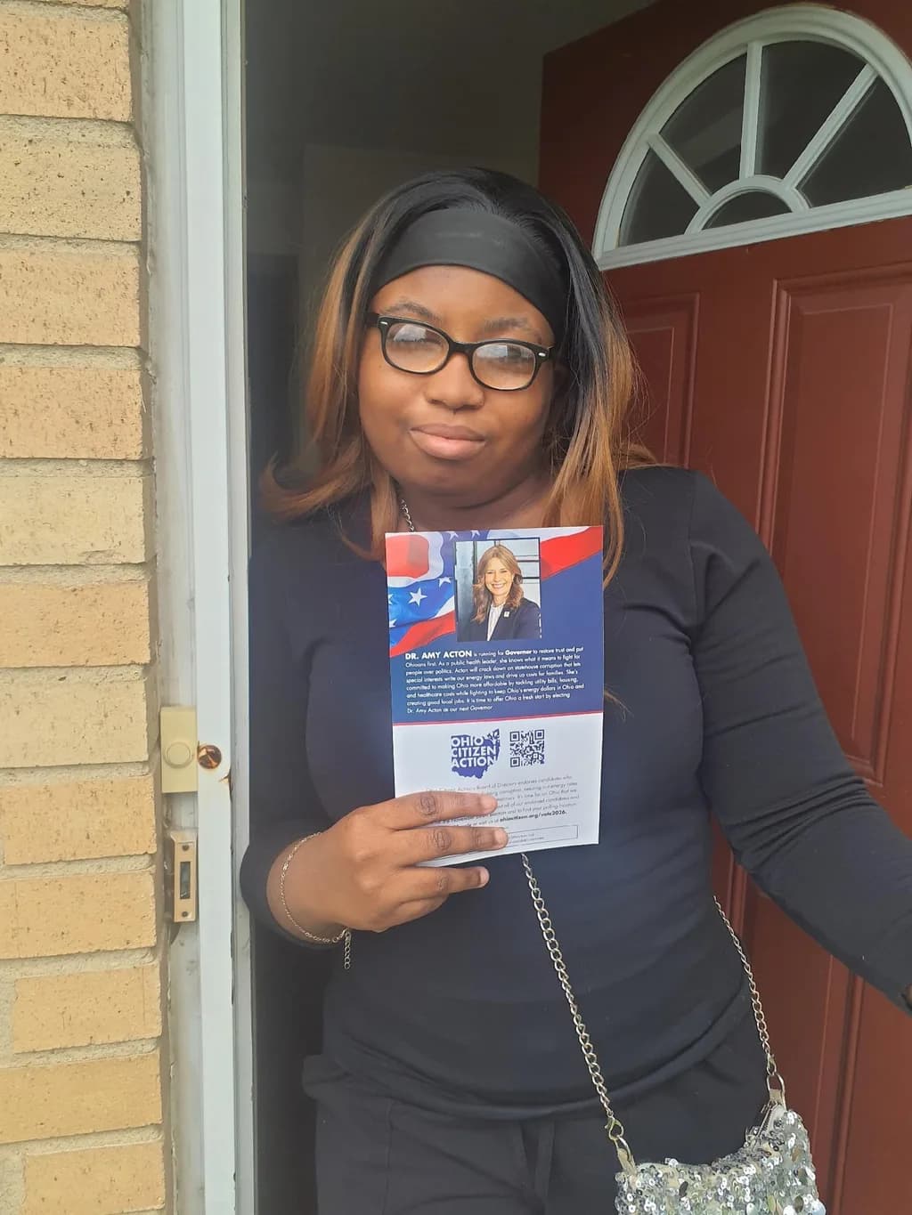 Stacia, a first-time voter, at her front door holding an Ohio Citizen Action flyer.