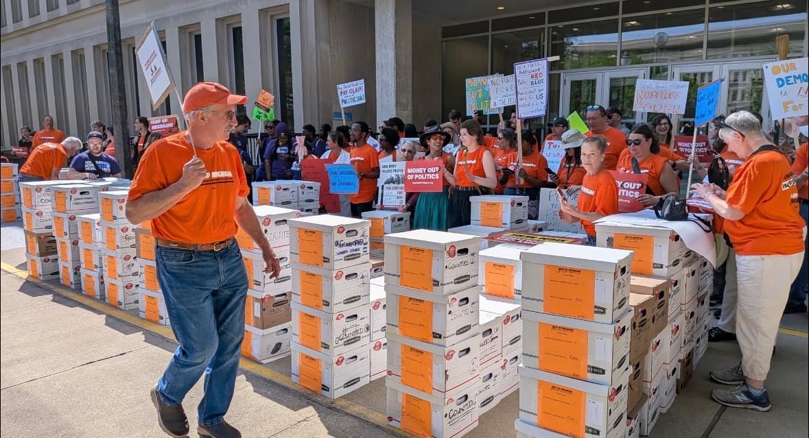 Photo: Michiganders for Money Out of Politics (MMOP) rallying with boxes of ballot initiative signatures.
